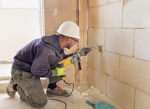 Electrical worker drilling and using specialized tools